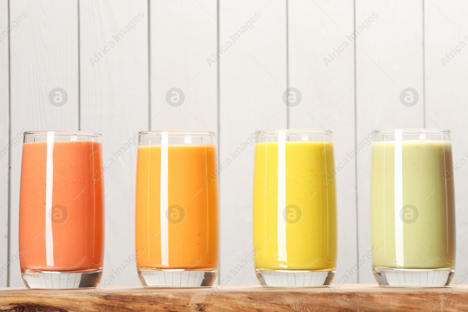 Photo of Board with many different tasty smoothies against white wooden background, space for text