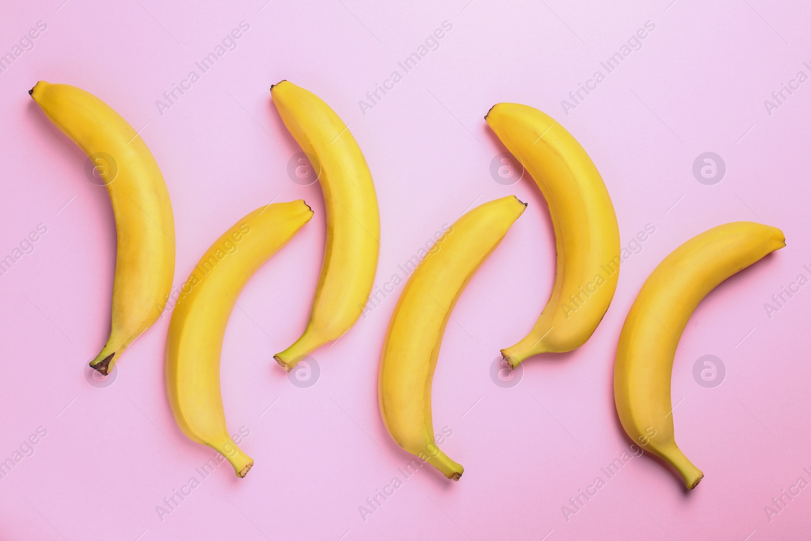 Photo of Ripe tasty bananas on pink background, flat lay