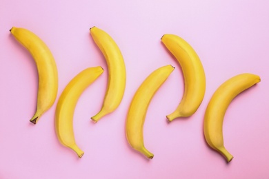 Photo of Ripe tasty bananas on pink background, flat lay