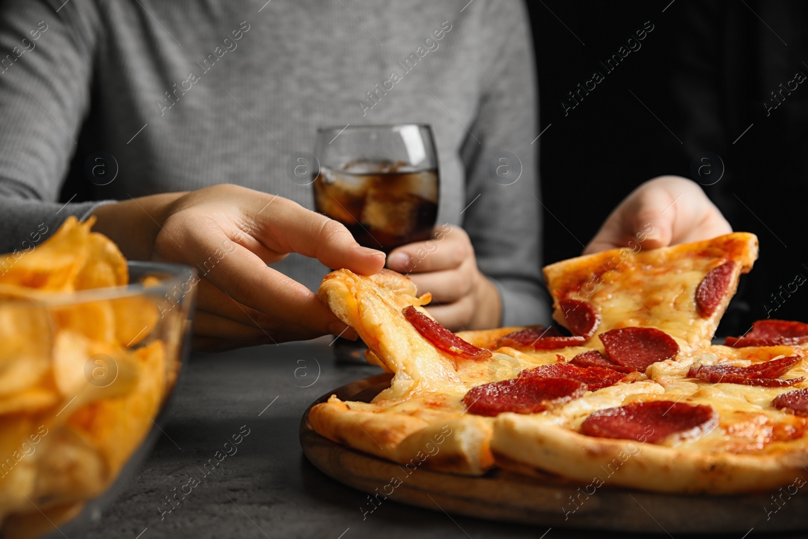 Photo of Women taking tasty pepperoni pizza at grey table, closeup