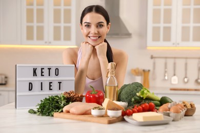 Happy woman near lightbox with words Keto Diet and different products in kitchen