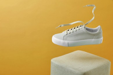 Photo of Stylish presentation of trendy sneaker on beige background. Space for text