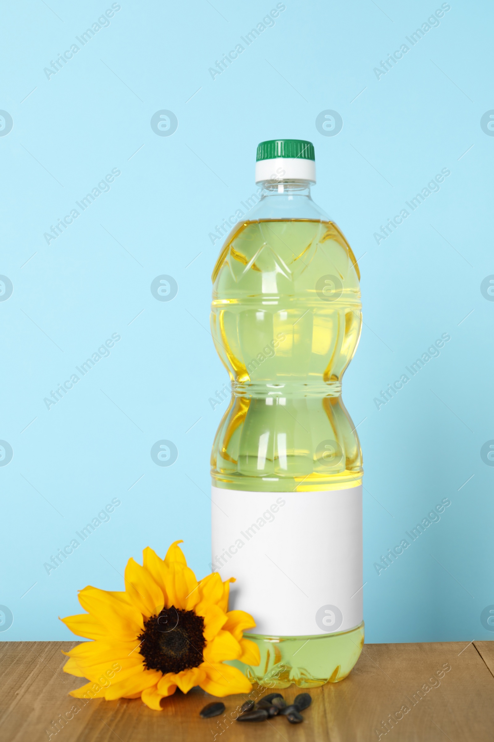 Photo of Bottle of cooking oil, sunflower and seeds on wooden table