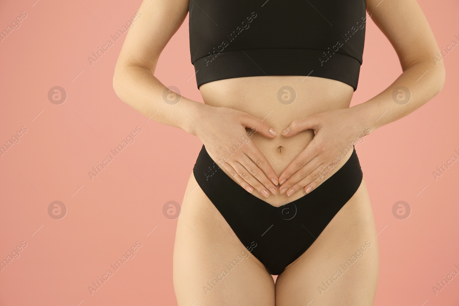 Photo of Gynecology. Woman in underwear making heart with her hands on pink background, closeup. Space for text