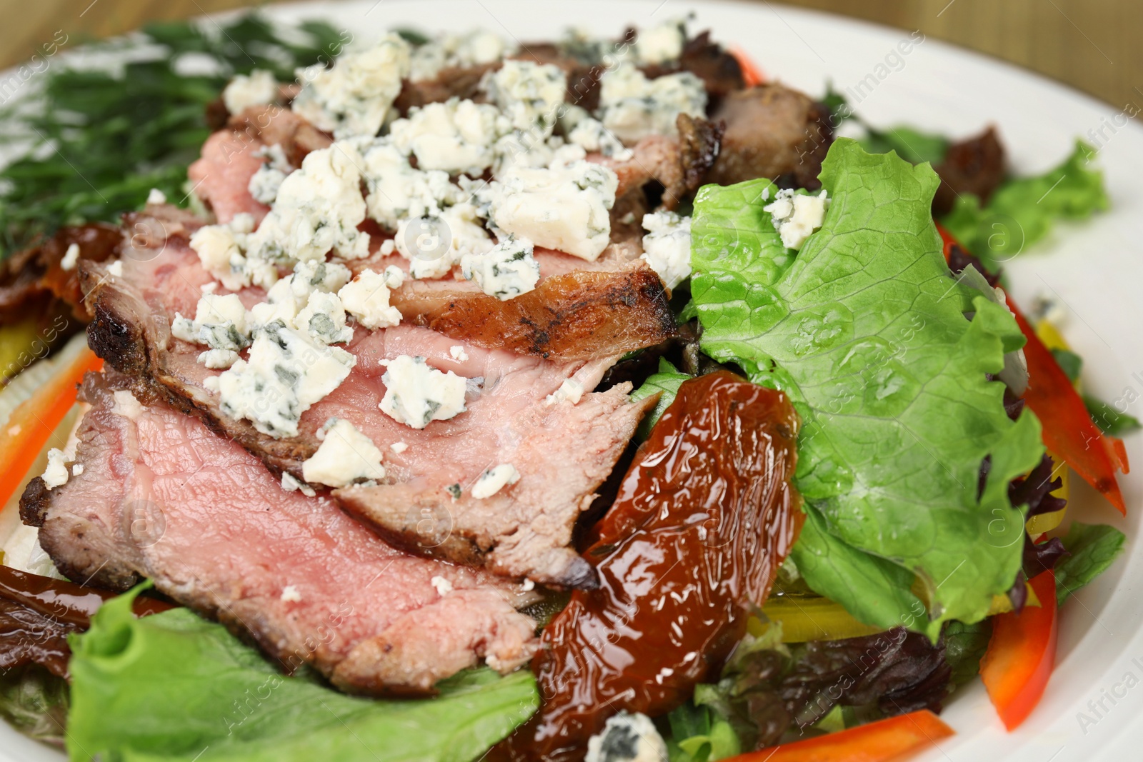 Photo of Delicious salad with roasted meat and vegetables on plate, closeup