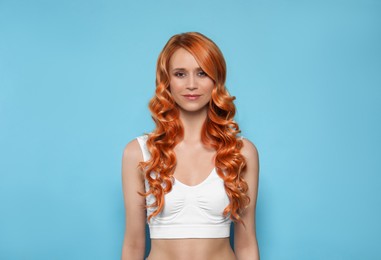Beautiful woman with long orange hair on light blue background