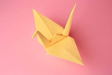 Photo of Origami art. Handmade paper crane on pink background, closeup