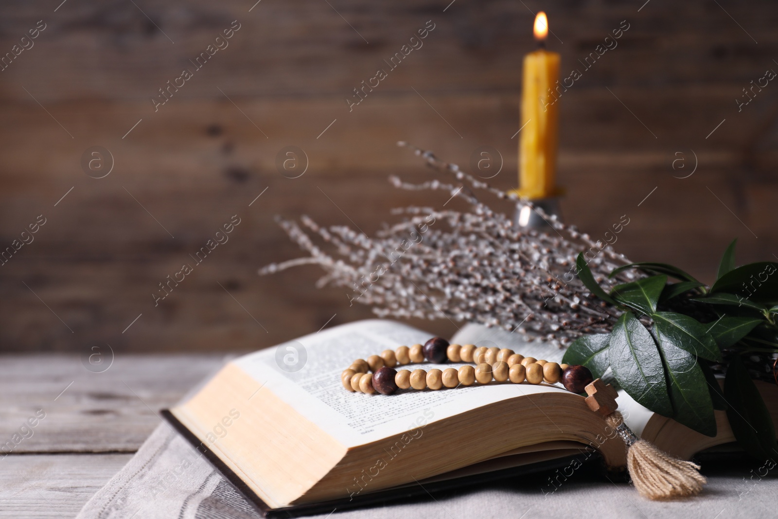 Photo of Rosary beads, Bible and willow branches on table, closeup