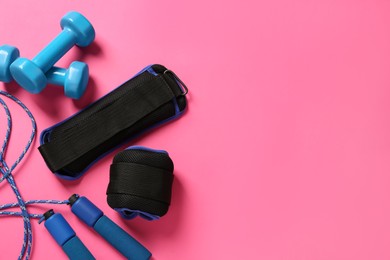 Blue weighting agents, dumbbells and skipping rope on pink background, flat lay. Space for text