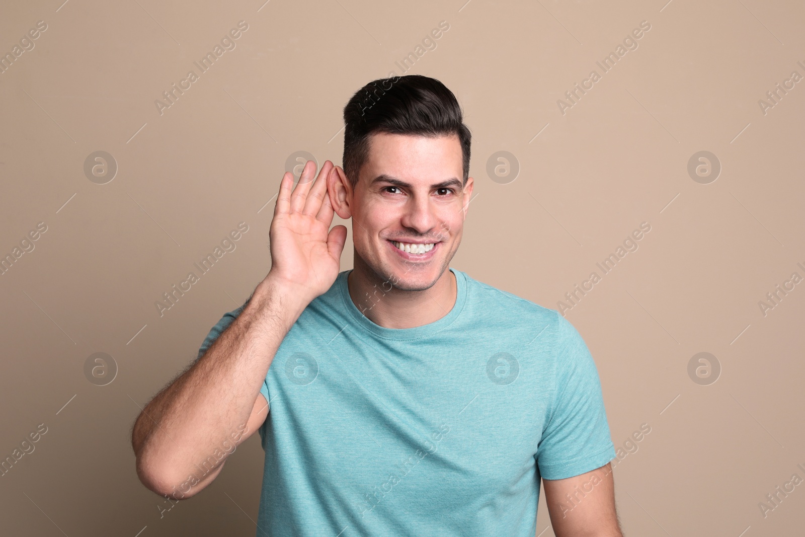 Photo of Man showing hand to ear gesture on beige background