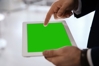 Businessman using digital tablet indoors, closeup. Device display with chroma key