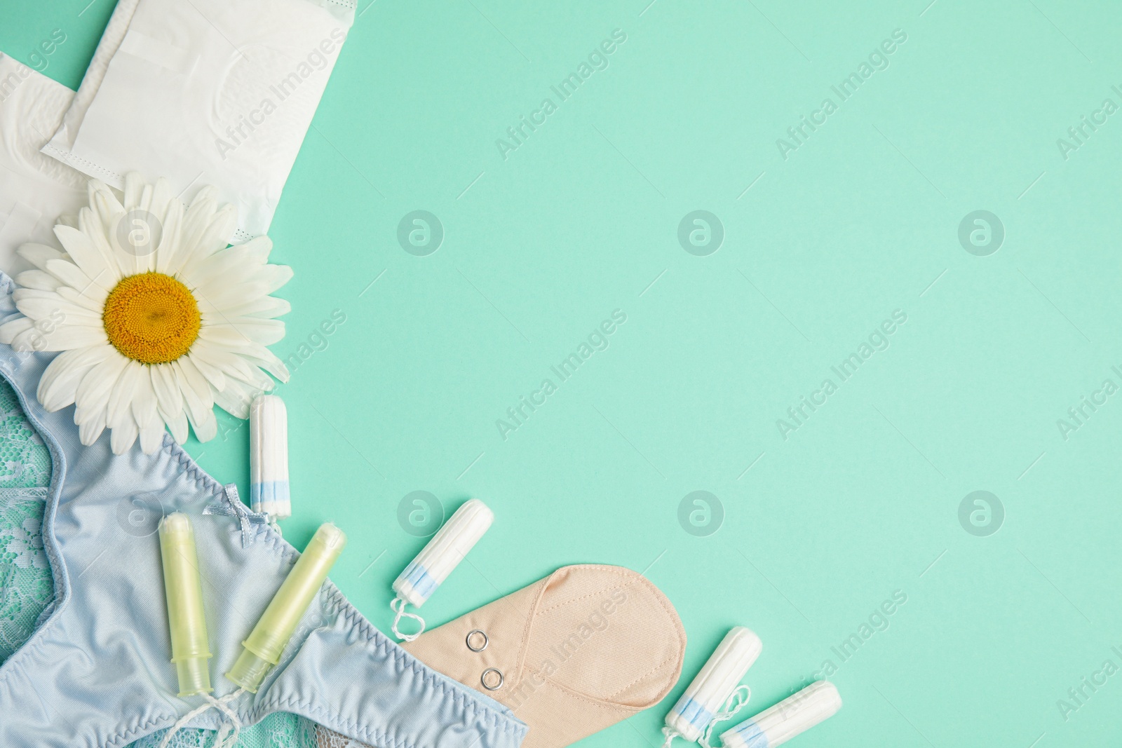 Photo of Tampons and other menstrual hygienic products on turquoise background, flat lay. Space for text