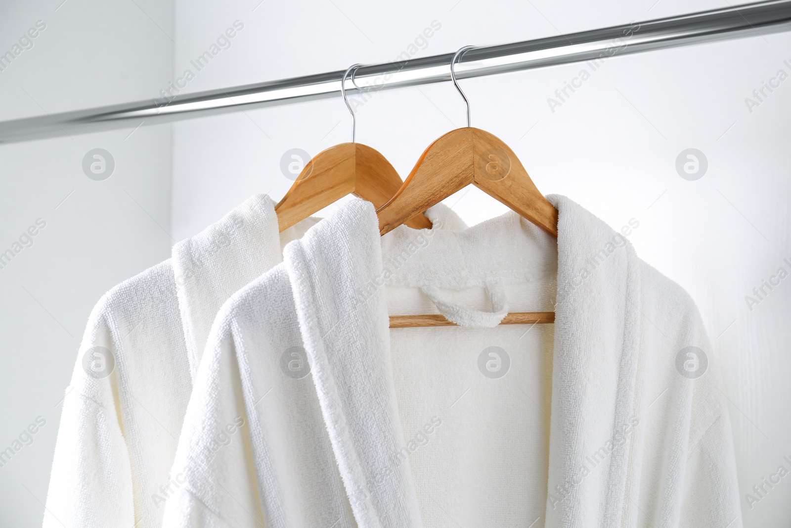 Photo of Soft comfortable bathrobes hanging on rack in closet