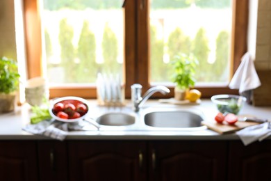 Photo of Blurred view of stylish kitchen interior with sink and products