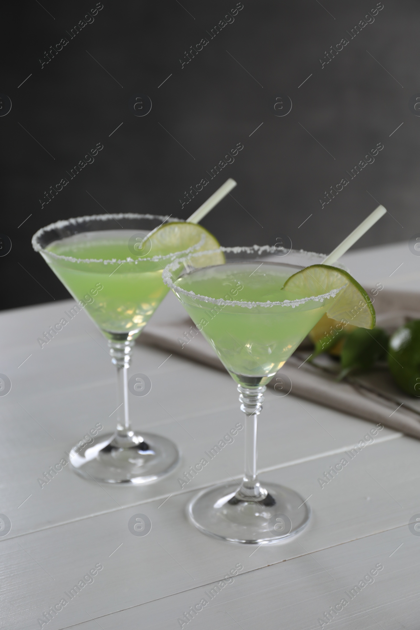 Photo of Delicious Margarita cocktail in glasses and lime on white wooden table