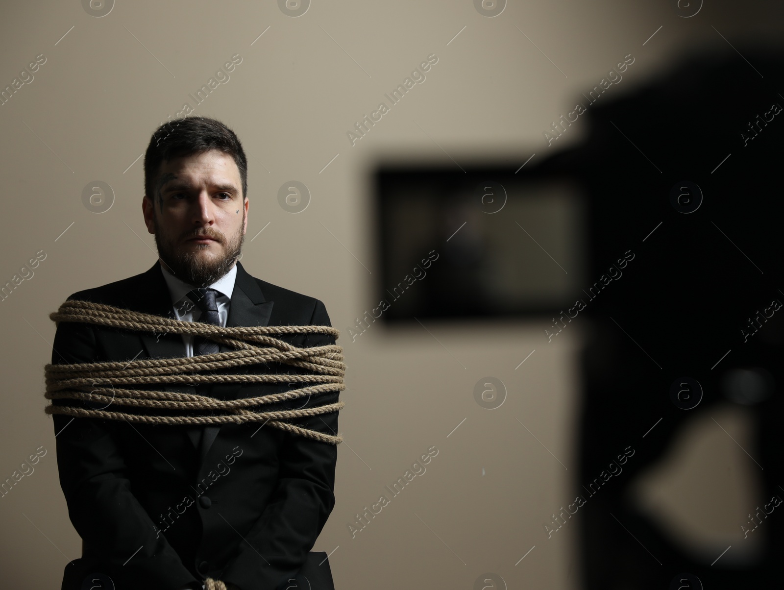 Photo of Man tied up and taken hostage near camera on grey background, selective focus