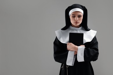 Photo of Nun with Bible on grey background, space for text