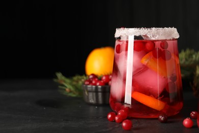 Photo of Tasty cranberry cocktail with ice cubes in glass on dark gray table, space for text