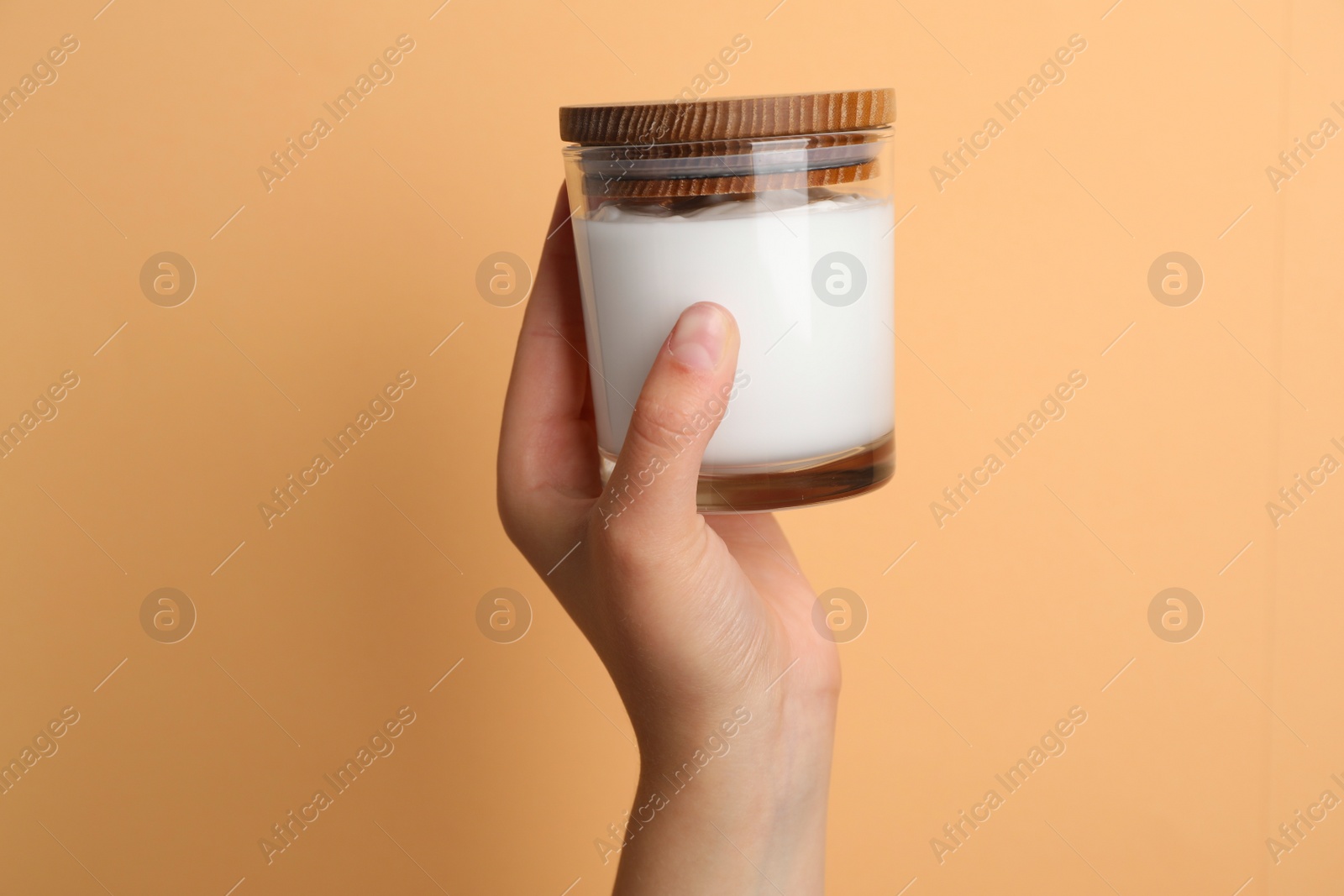 Photo of Woman holding jar of face cream on coral background, closeup