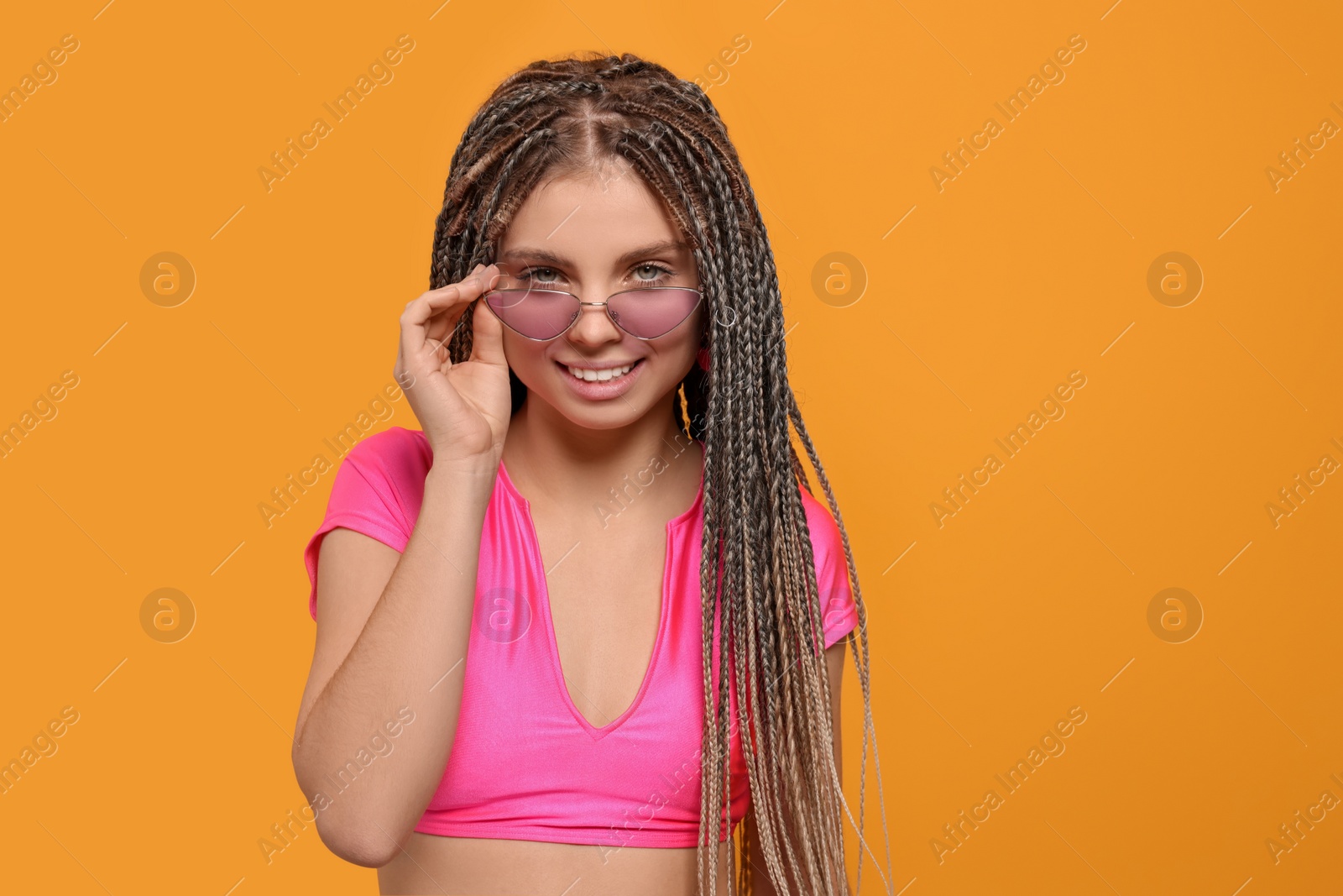 Photo of Beautiful woman with long african braids on yellow background, space for text