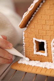 Woman decorating gingerbread house with icing, closeup