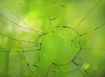 View through broken window on blurred green background