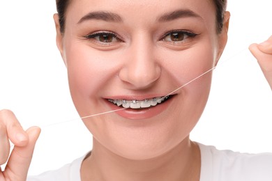 Smiling woman with braces cleaning teeth using dental floss on white background, closeup