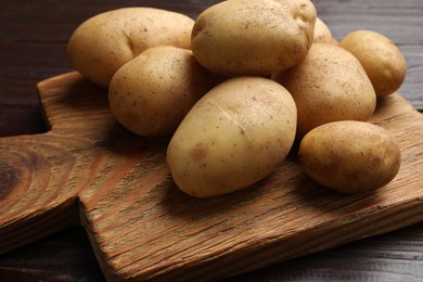 Photo of Raw fresh potatoes and cutting board on wooden table