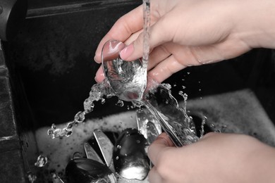 Photo of Woman washing silver kitchenware under stream of water in sink, closeup