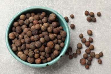 Photo of Aromatic allspice pepper grains in bowl on grey table, top view