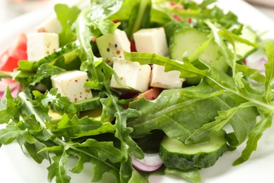 Photo of Delicious salad with feta cheese, arugula and vegetables on plate, closeup