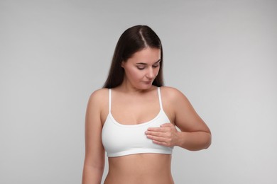 Photo of Mammology. Woman doing breast self-examination on light grey background