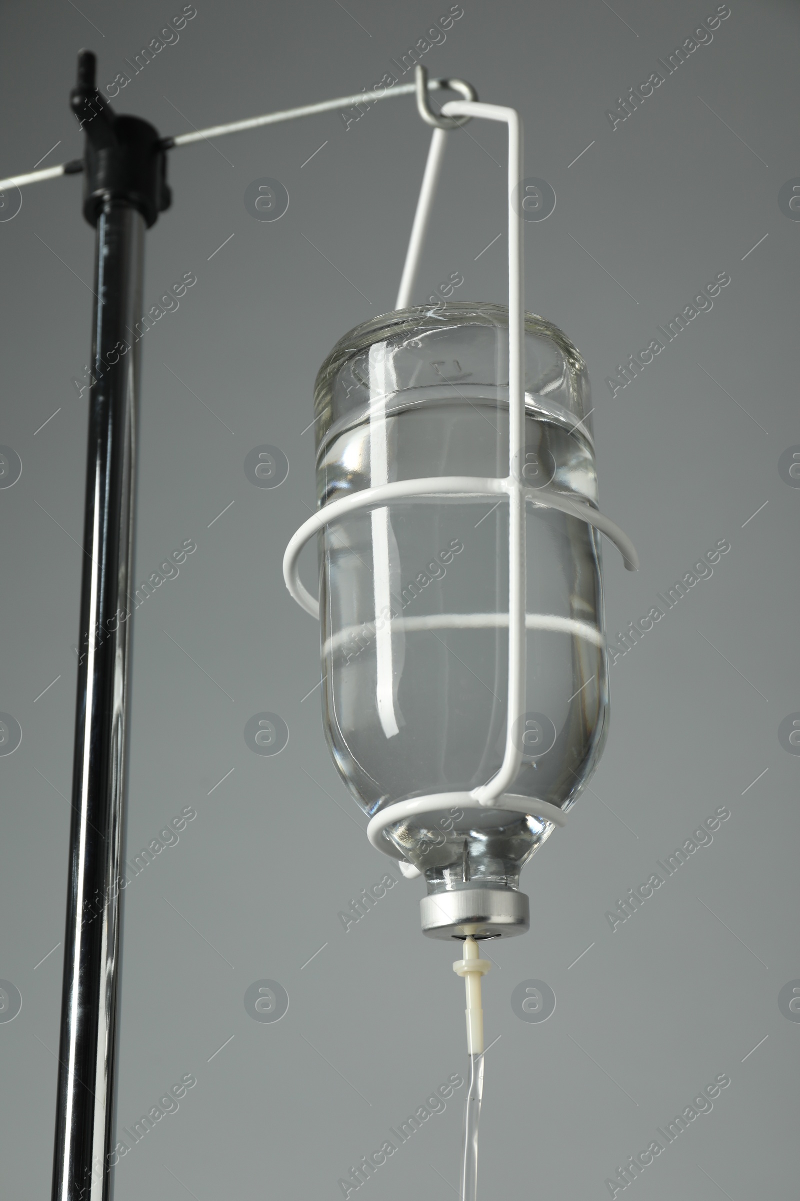 Photo of IV infusion set on pole against grey background, closeup