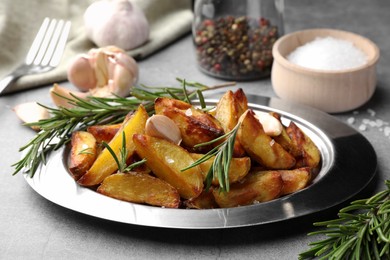 Tasty baked potato and aromatic rosemary served on grey textured table, closeup