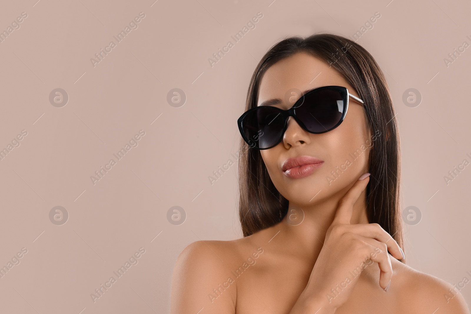 Photo of Beautiful young woman wearing sunglasses on beige background. Space for text