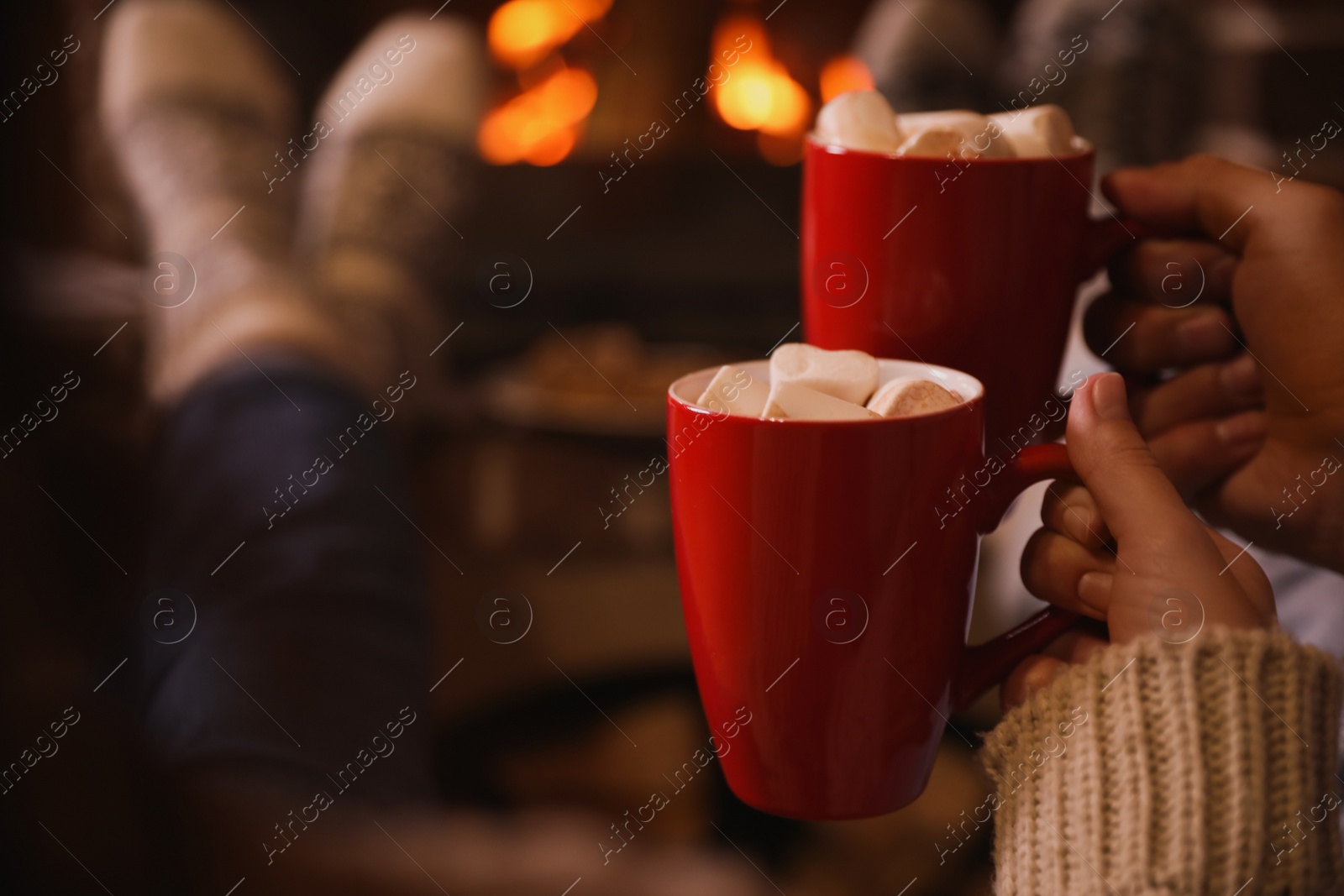 Photo of Lovely couple with sweet cocoa near fireplace indoors, closeup