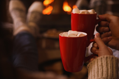 Lovely couple with sweet cocoa near fireplace indoors, closeup