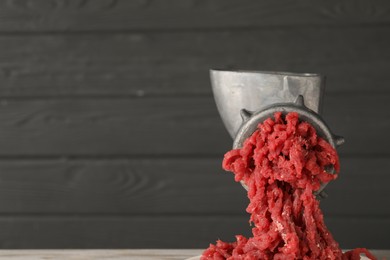 Photo of Metal meat grinder with beef mince against grey background. Space for text