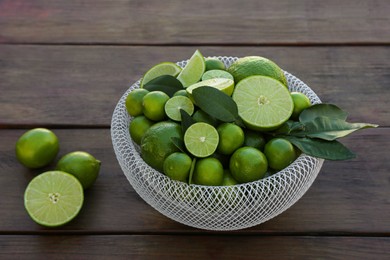 Photo of Fresh ripe limes and green leaves on wooden table