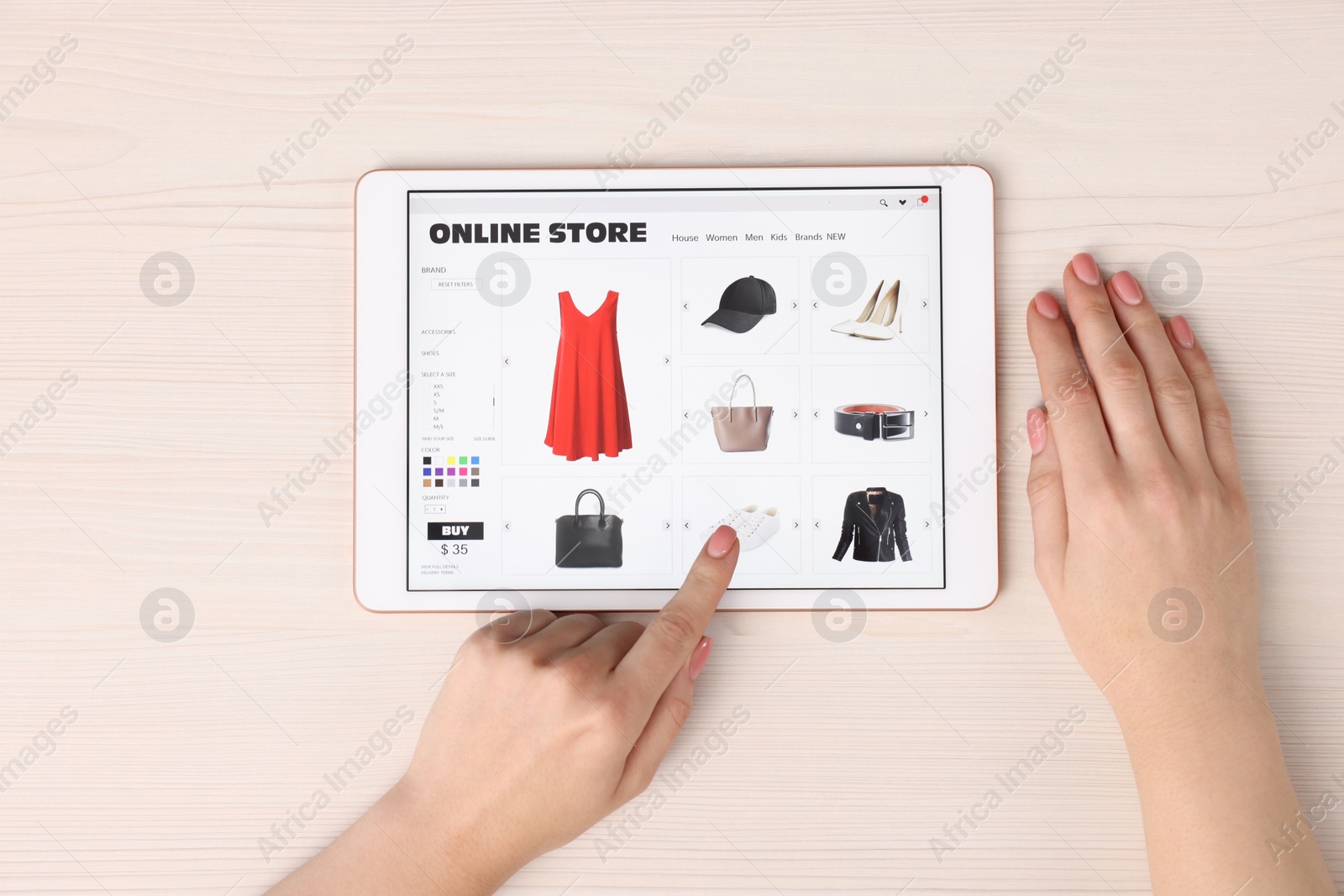 Photo of Woman with tablet shopping online at white wooden table, top view