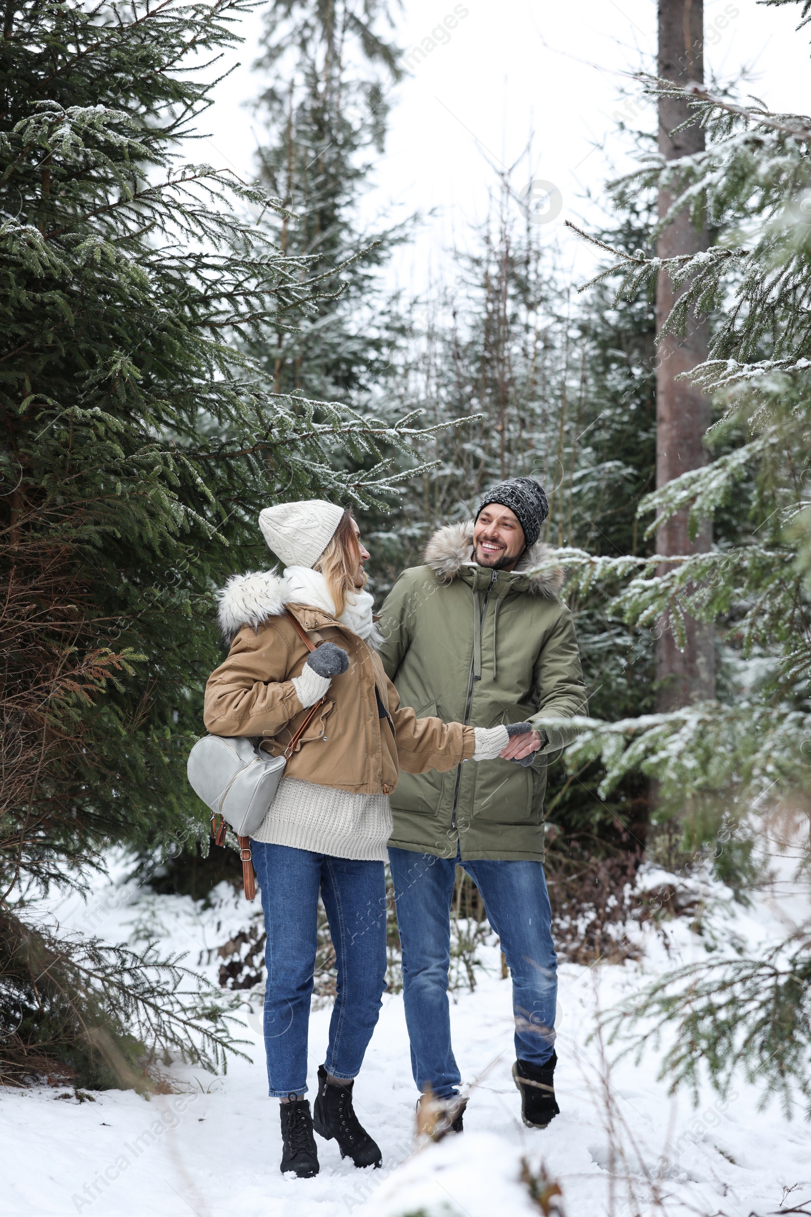 Photo of Couple in conifer forest on snowy day. Winter vacation