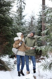 Photo of Couple in conifer forest on snowy day. Winter vacation