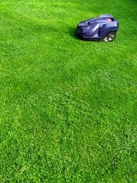 Modern robot lawn mower on green grass in garden