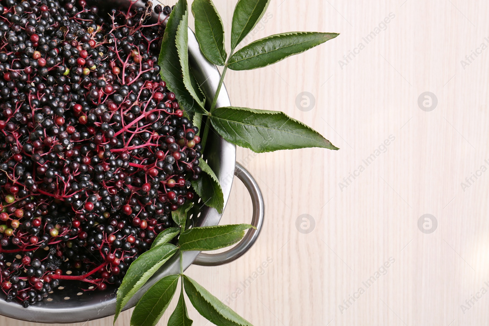 Photo of Tasty elderberries (Sambucus) on wooden table, top view. Space for text