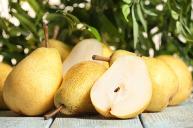 Photo of Fresh ripe pears on wooden table against blurred background