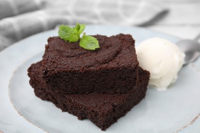 Photo of Tasty brownies served with ice cream and mint on table, closeup