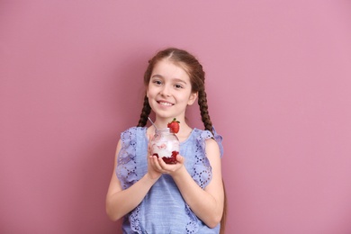 Cute girl eating tasty yogurt on color background