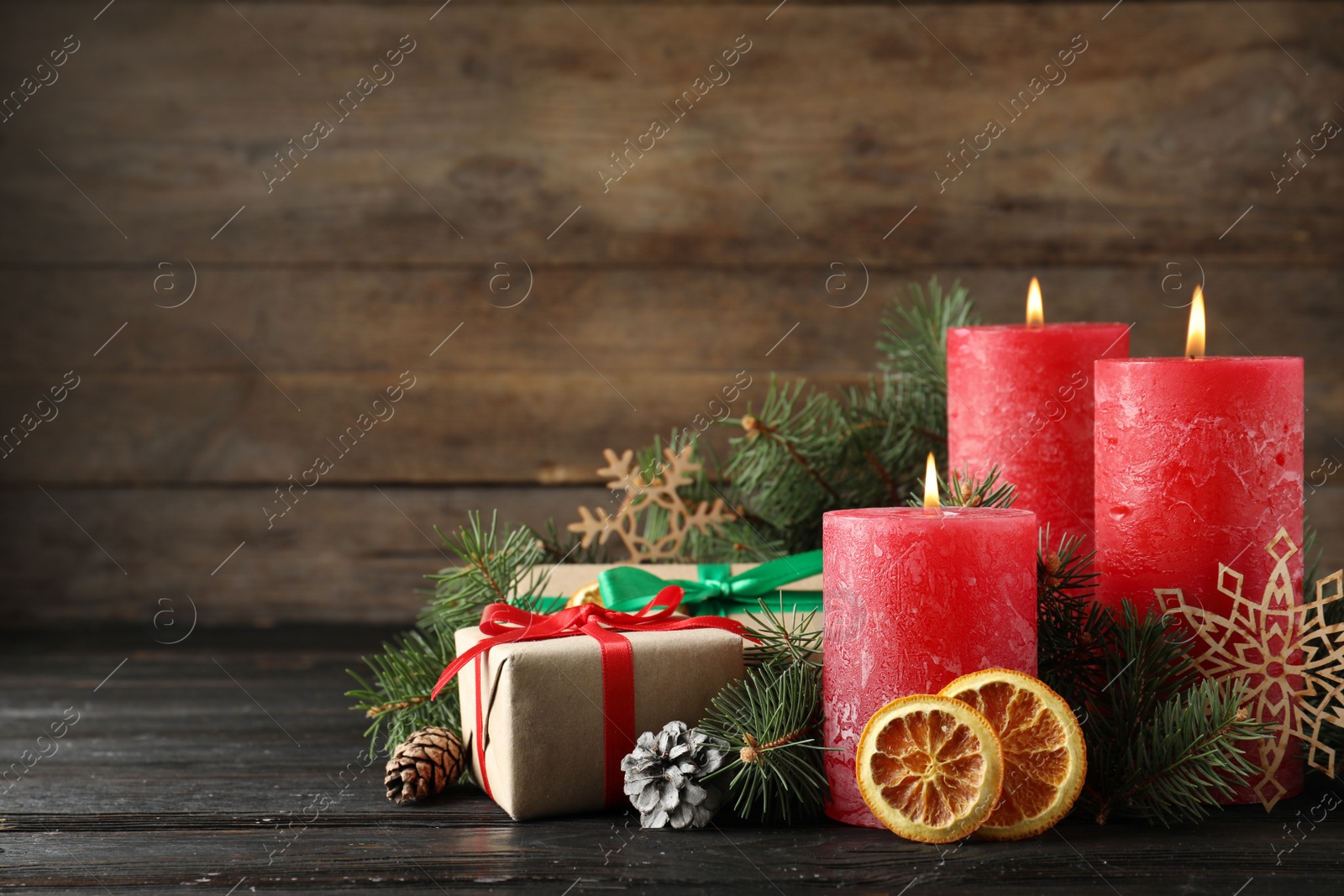 Photo of Beautiful Christmas composition with burning red candles on wooden background. Space for text