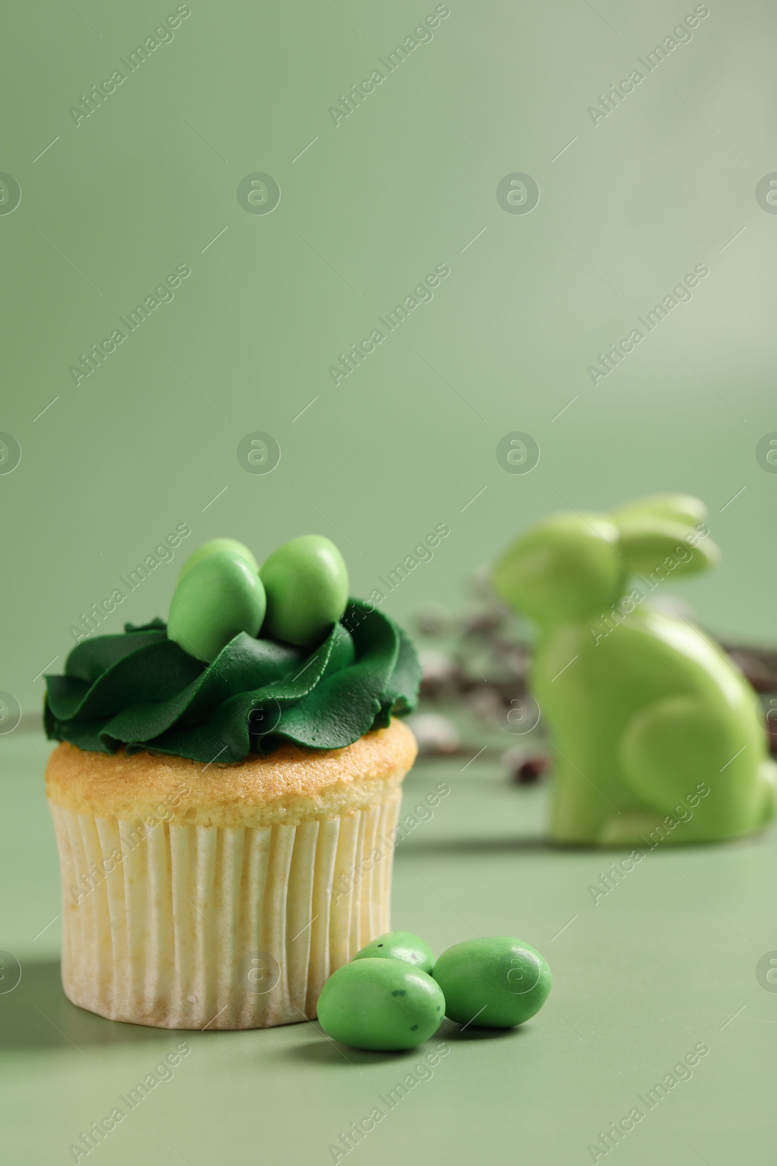 Photo of Tasty cupcake with Easter decor on green background, closeup