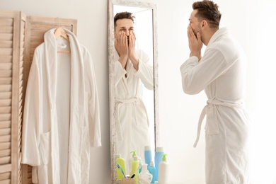 Young man looking at himself in mirror indoors